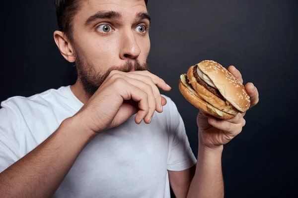 Man eten hamburger fast food restaurant Gourmet eten donkere achtergrond — Stockfoto