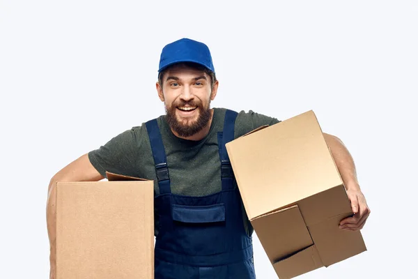 Ein Mann in Arbeitsuniform mit einer Schachtel in der Hand liefert Transportarbeiten aus — Stockfoto
