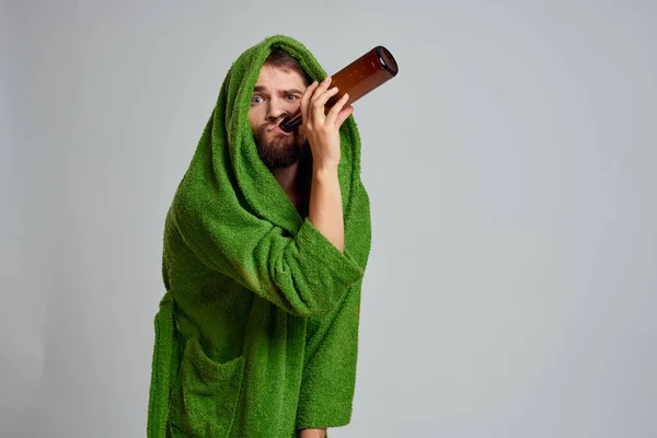 Homem bêbado com garrafa de álcool na mão e roupão verde bebendo relaxamento — Fotografia de Stock
