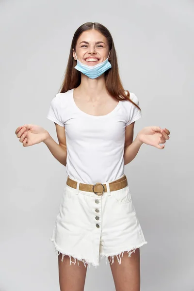 Kvinna i medicinsk mask leende vit t-shirt — Stockfoto