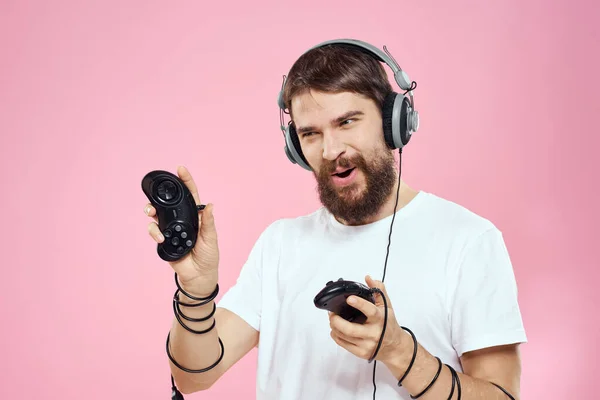 Man in hoofdtelefoon met joysticks in handen spelen spelletjes lifestyle plezier entertainment roze achtergrond — Stockfoto