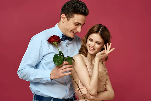 Verliebte Menschen mit Rose in den Händen auf rosa isoliertem Hintergrund umarmen Emotionen Glück romantische Gefühle — Stockfoto