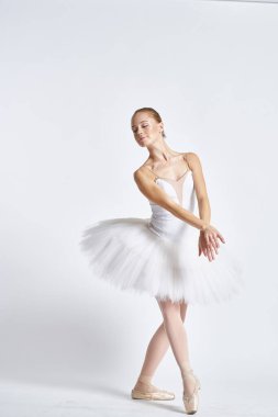 Beyaz etekli bir balerin hafif bir arka planda dans etti.