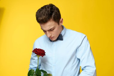 Gömlekli ve papyonlu bir beyefendi boynunda sarı arka planda kırmızı gül