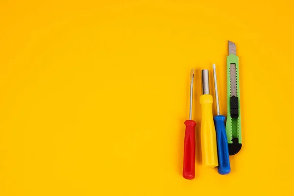 Śrubokręty do noży do papieru i narzędzia budowlane na żółtym tle urządzenia dla przemysłu naprawczego — Zdjęcie stockowe