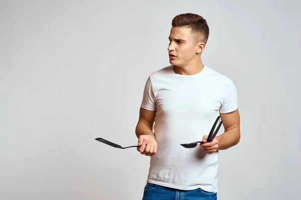 Cara com ferramentas de cozinha em mãos em um fundo leve corte vista de emoções divertido modelo — Fotografia de Stock