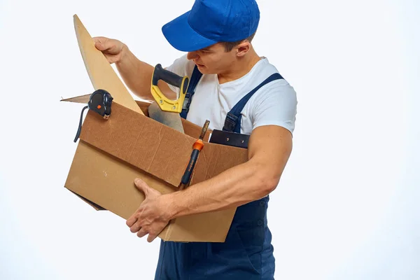 Mężczyzna w roboczym mundurku z pudełkiem w ręku, ładujący dostawę. — Zdjęcie stockowe