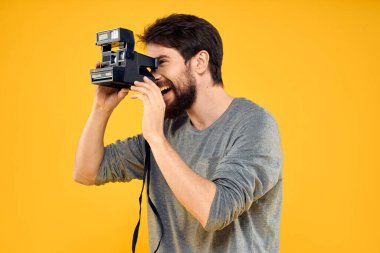 Profesyonel fotoğraf makinesi olan bir erkek fotoğrafçı. Profesyonel Yaratıcı yaklaşım stüdyo sarı arka plan