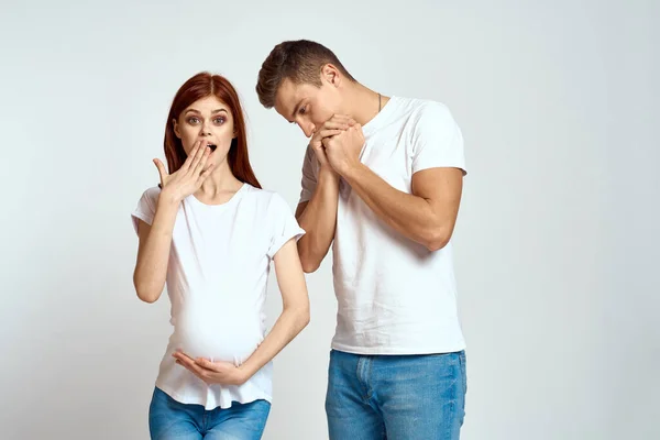 Беременная женщина и молодой человек ждут ребенка на легком фоне эмоций семьи любовь — стоковое фото