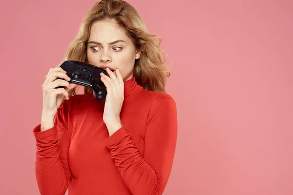 Vrouw met gamepad in de hand entertainment video games lifestyle technologie rode blouse roze achtergrond — Stockfoto