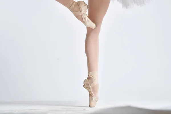Балерина в белой балетной пачке исполняется на светлом фоне — стоковое фото