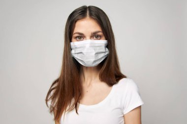 Yüzüne tıbbi maske takmış bir kadın. Önüne bak, beyaz tişört. 