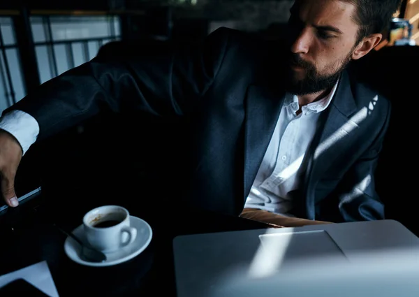 Homem de negócios de terno no café na frente do laptop com uma xícara de bebida oficial — Fotografia de Stock