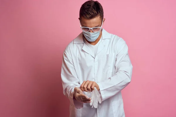 Лікар в медичних рукавичках з маскою для обличчя на рожевому фоні обрізаний вид — стокове фото