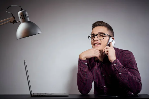 Hombre de negocios en gafas y una camisa se sienta en una mesa con ordenadores portátiles abiertos Café Espacio teléfono móvil — Foto de Stock