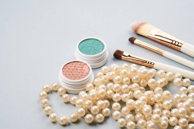 Göz farı aksesuarları, makyaj fırçaları, gri arka planda profesyonel kozmetik ürünleri.