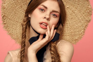 Hasır şapkalı bir kızın portresi pembe arka plan duyguları yakın plan güzel yüz modeli örgüler.