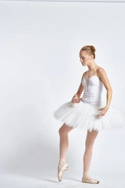 Bailarina em um tutu branco realizando dança exercício flexibilidade luz fundo — Fotografia de Stock