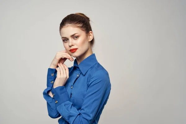 En elegant dam i blå skjorta gester med händerna på en ljus bakgrund och en kopia utrymme närbild porträtt — Stockfoto