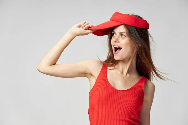 En glad kvinna med en mössa på huvudet tittar mot sin röda t-shirt — Stockfoto
