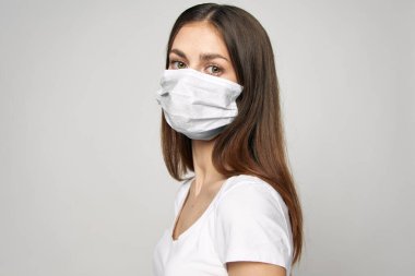 Tıbbi maske takan kadın önüne bakıyor. 