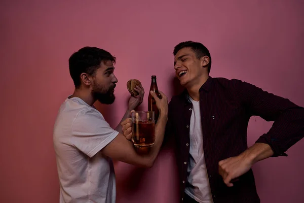 Двое мужчин пьют пиво дружба пьяный алкоголь образ жизни розовый фон — стоковое фото