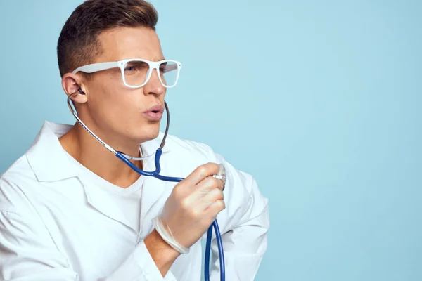 가운 과 안경 을 착용하고 있는 의료인이 푸른 배경이 갈라진 경치를 손에 들고 청진기를 들고 있다 — 스톡 사진