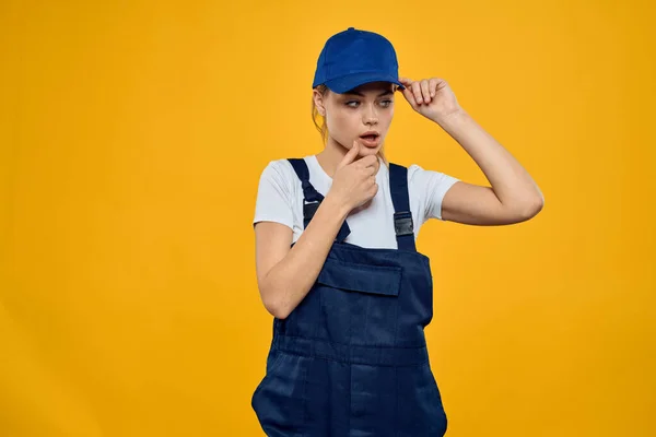 Mujer en uniforme de trabajo gorra azul entrega servicio de mensajería fondo amarillo —  Fotos de Stock