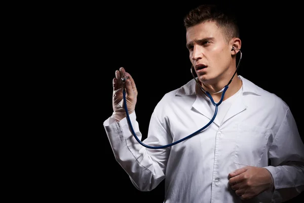 Medico professionista in un abito medico con uno stetoscopio intorno al collo contro uno sfondo scuro vista ritagliata — Foto Stock