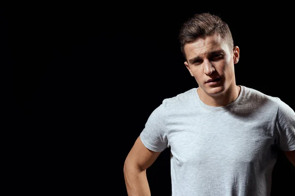 Hombre guapo en camiseta blanca sobre fondo negro inflado músculos del brazo modelo deportivo recortado ver Copiar el espacio —  Fotos de Stock