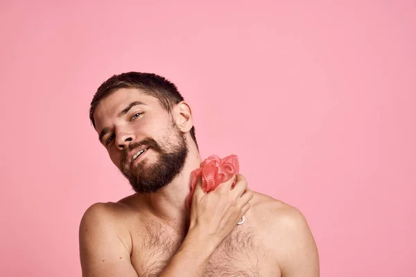 Homem com ombros nus com uma toalha na mão tomando um chuveiro pele limpa fundo rosa — Fotografia de Stock