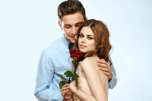 Hombre y mujer con una rosa roja sobre un fondo claro amor abrazos familiares — Foto de Stock