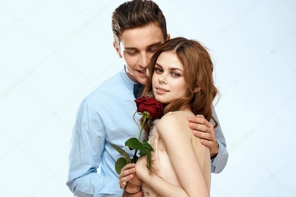 Man and woman with a red rose on a light background love family hugs