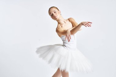 Beyaz etekli balerin dans egzersizi yapıyor. Esnek arka plan.