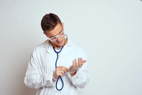 Médecin dans une robe médicale avec un stéthoscope et des lunettes sur un fond clair portrait de vue recadrée — Photo