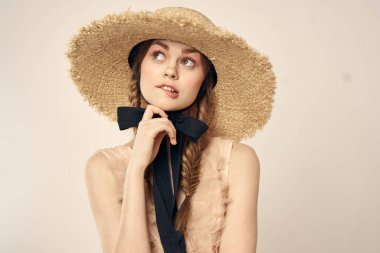 Bej elbiseli, hasır şapkalı, siyah kurdele takmış, manken görünümlü romantik bir kız.