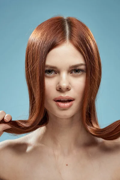 Vacker kvinna som håller hår i händerna grooming nakna axlar beskärda visa blå bakgrund — Stockfoto