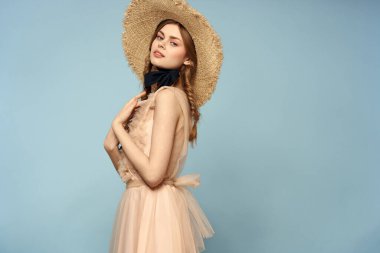 Mavi arka planda pembe elbiseli bir kız elleriyle romantik modeller yapıyor.