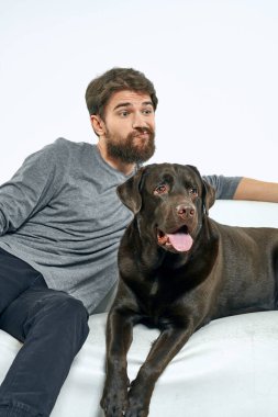 Beyaz bir kanepede siyah köpeği olan bir adam. Arka planda, yakın planda kesilen evcil hayvan insan arkadaş duyguları. Eğlenceli.