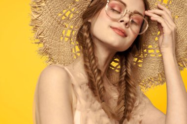 Saçları örgülü ve sarı arka planda şapkası olan güzel bir kadının portresi.
