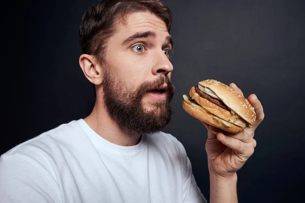 Ο άνθρωπος τρώει χάμπουργκερ fast food εστιατόριο Gourmet τρώει σκούρο φόντο — Φωτογραφία Αρχείου