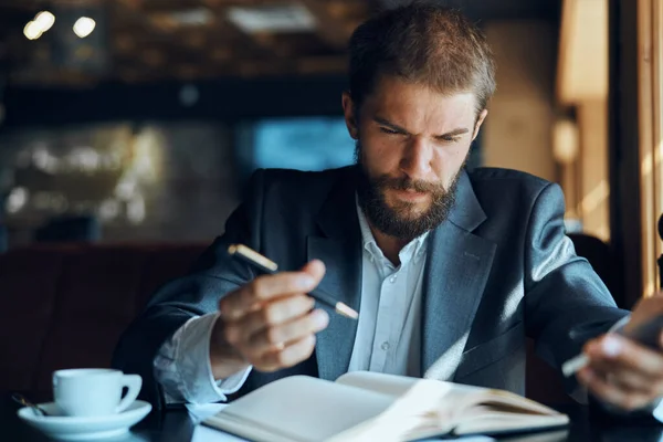 Uomo d'affari seduto a un tavolo in un caffè documenti di lavoro tazza di caffè ufficiale — Foto Stock