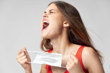 Kapalı gözlü, ağzı açık tıbbi maske takan duygusal bir kadın.