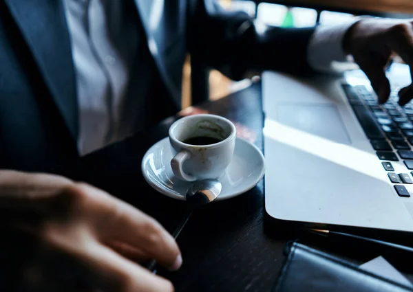 Επιχειρηματίας σε ένα καφέ στο τραπέζι μπροστά από ένα φορητό υπολογιστή εργασία ένα φλιτζάνι καφέ στο τραπέζι τεχνολογία επικοινωνίας — Φωτογραφία Αρχείου