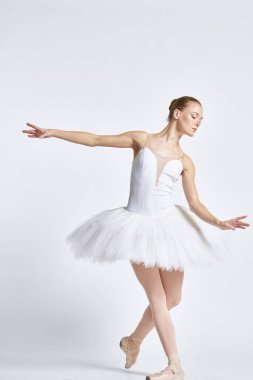 Beyaz etekli bir balerin hafif bir arka planda dans etti.