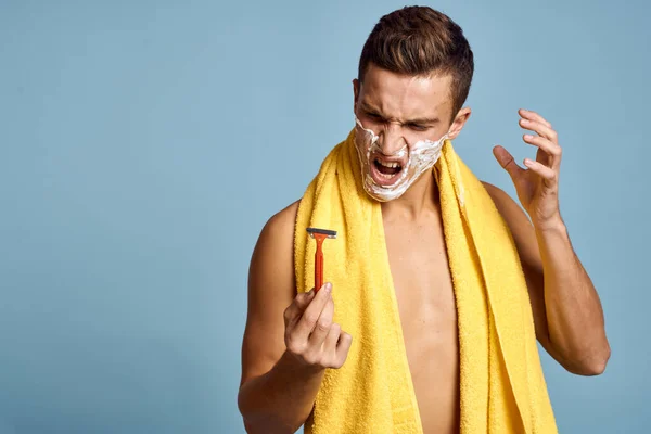 Hombre con afeitadora sobre fondo azul y espuma blanca toalla amarilla vista recortada — Foto de Stock