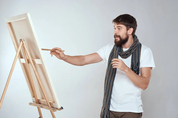 A man artist draws on an easel a scarf white t-shirt art hobby creativity
