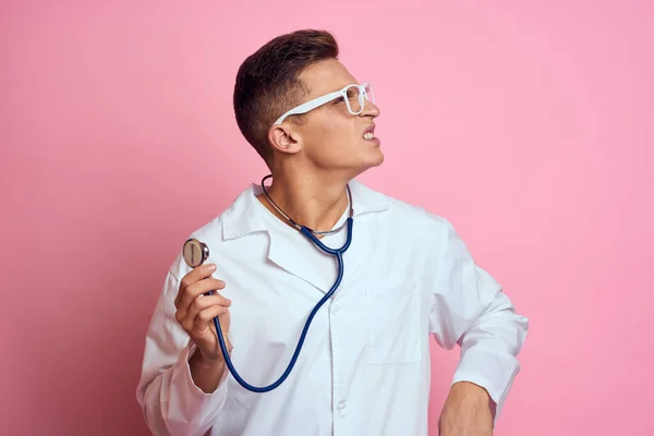 Jeune médecin avec un stéthoscope et des lunettes sur fond rose infirmière stagiaire modèle — Photo