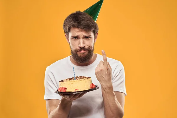 Бородатый мужчина с тортом и в кепке, празднующий свой день рождения — стоковое фото