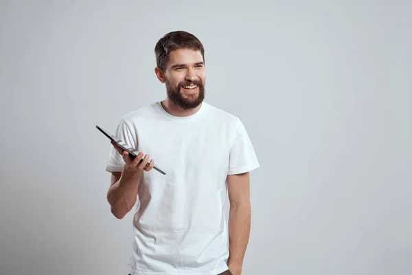 Чоловік у білій футболці з планшетом в руках емоції технологія світлого фону — стокове фото